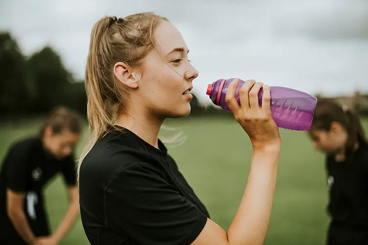 Girl drinking a water bottle at soccer practice