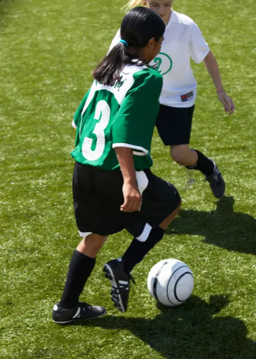 A youth soccer player taking on an opponent in a 1v1 battle