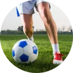 A female soccer player dribbles a blue and white soccer ball on a grass field
