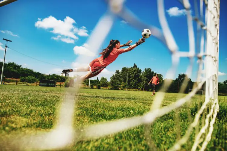 A female goalkeeper makes a diving save during soccer practice