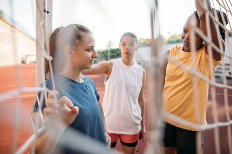 A group of young women stretches next to a track before starting a run