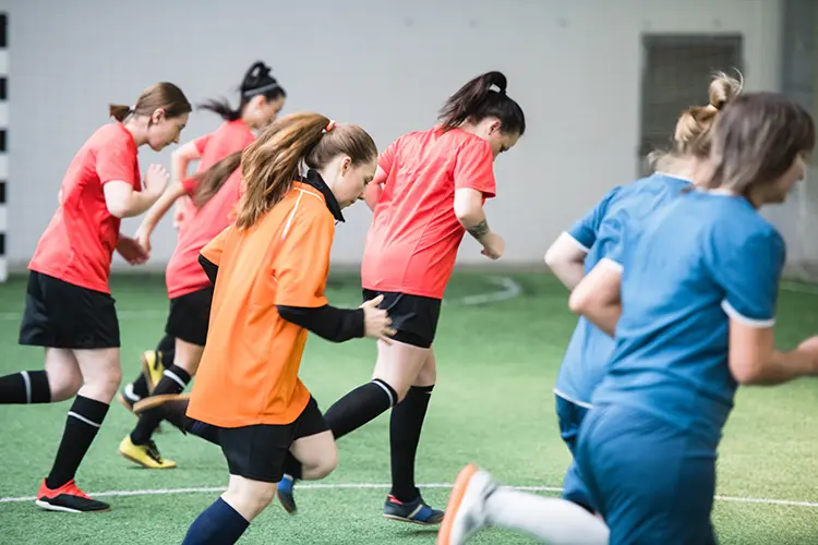 Group of girls warming up for soccer in different colored tops