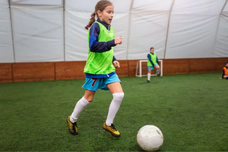 A youth female player dribbles at at indoor soccer facility