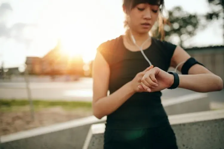 A jogger checks her watch before starting her run in the evening