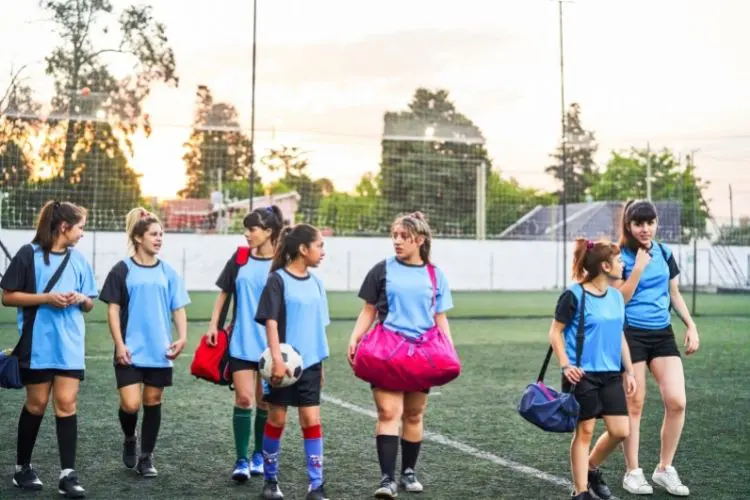 A girls soccer team walks away from the training field with all of their gear