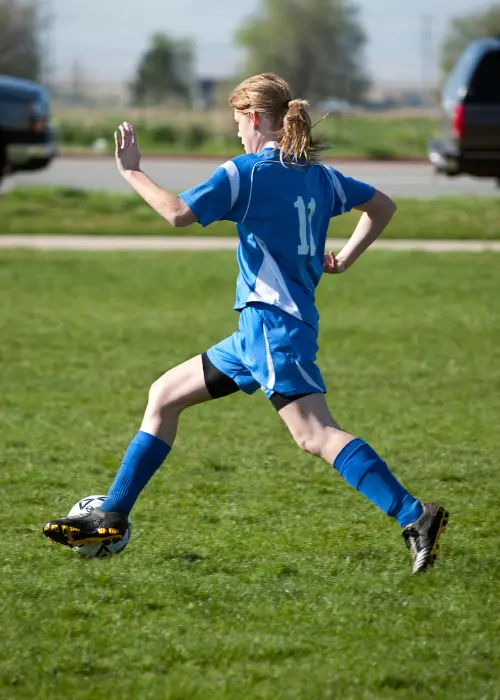 Girl dribbles a soccer ball up the field during a game