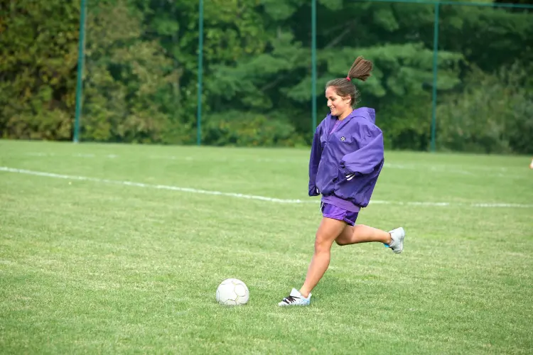 High school soccer player warming up by passing the ball with her teammate before a game