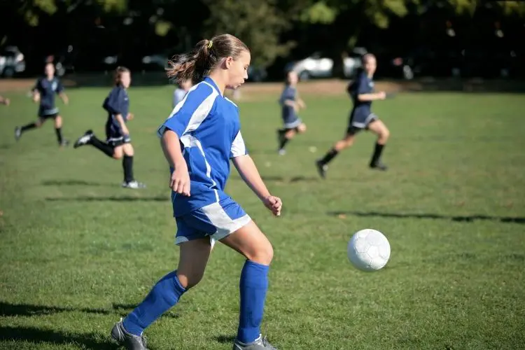A soccer player looks at the ball as she is about to receive a pass during a soccer game