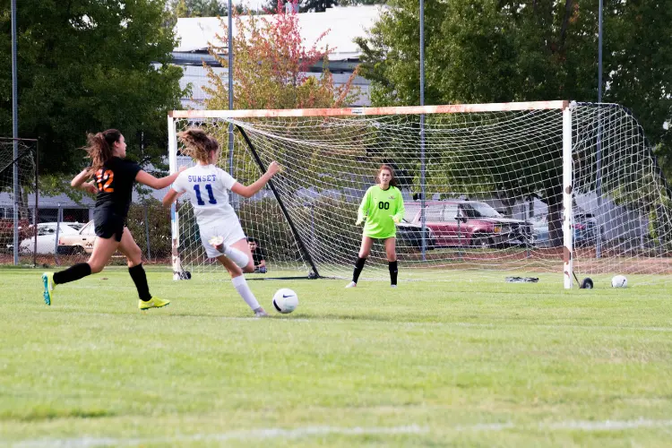 A defender loses her mark and a player is about to strike the ball and take a shot on goal during a soccer game