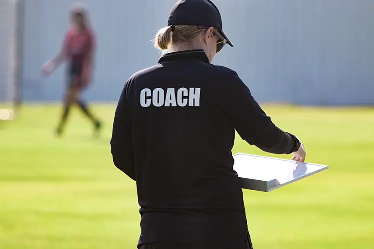 Female soccer coach with a clipboard on the field