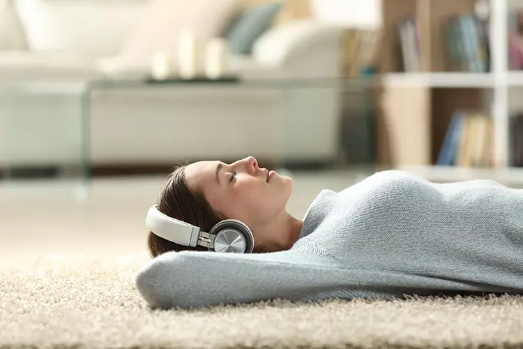 Young woman relaxing on the floor with her eyes closed and headphones on