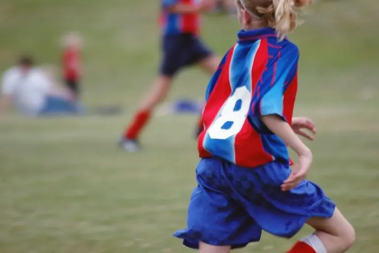 A youth soccer player runs up the field